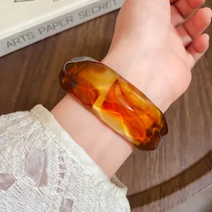Close-up of faceted acrylic bangle with amber marbled texture on wrist