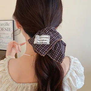 Λεπτομερής προβολή καφέ καρό scrunchie με κεντημένο επίθεμα κειμένου Dreamer.
