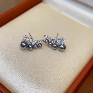 Detailed view of curved stud earrings with grey pearls and sparkling cubic zirconia stones