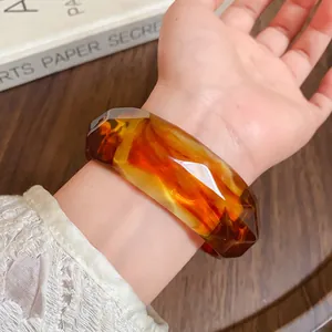 Detailed view of an amber marbled acrylic faceted bangle on a wrist for a stylish look