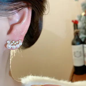 Close-up detail of 18K gold plated zircon pearl stud earrings on model's ear