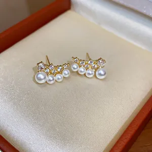 Detail view of gold-plated stud earrings with elegant pearls and sparkling zircons