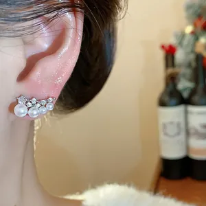 Close-up view of elegant 18k gold plated pearl and zircon curved stud earrings worn on ear