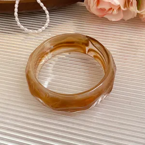 Detail view of a marbled amber acrylic faceted bangle with unique swirling textures.