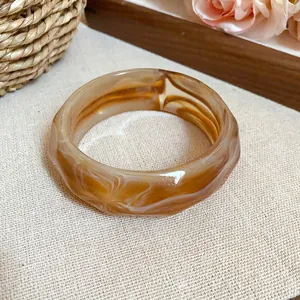 Close-up of marbled acrylic faceted bangle with brown and white swirled pattern