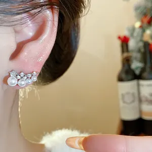 Detailed close-up of an 18k gold-plated pearl and cubic zirconia stud earring on an ear.
