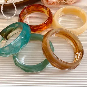 Close-up of acrylic marbled bangles with faceted edges in various earth-tone colors.