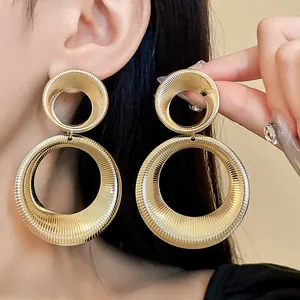 Close-up of large gold-toned double hoop earrings with textured finish on model