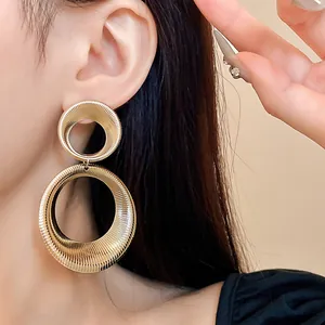 Close-up detail of oversized golden textured metal circular drop earrings for women.