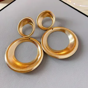 Close-up of textured gold circular drop earrings with ribbed metallic finish