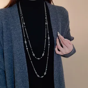 Detailansicht einer langen Vintage-Halskette mit Blumen und Perlen an einem Model