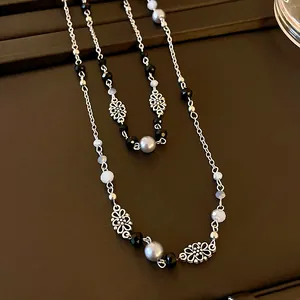 Detailansicht der langen Vintage-Pulloverkette mit Blumenmotiven und Kunstperlen.