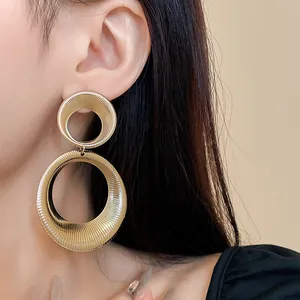 Detail shot of chunky gold metal hoop earrings with elegant ribbed texture for women