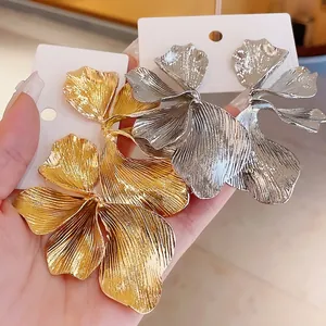 Large metallic floral stud earrings in gold and silver finish with textured flower petals