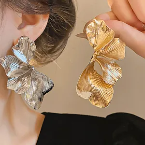Detailed macro view of large metallic flower earrings in gold and silver finish