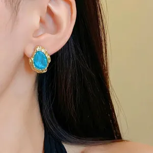 Retro vergoldete Ohrstecker mit blauem Sternsand-Tropfen-Inlay am Modell