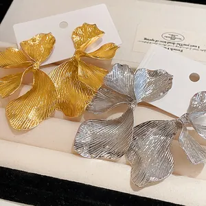 Detailed macro view of gold and silver flower petal earrings with textured surface