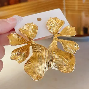 Detailed view of large gold metallic flower petal earrings with textured finish