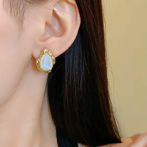 Detailansicht der goldenen geometrischen Vintage-Ohrstecker mit Perlmuttzentrum am Ohr