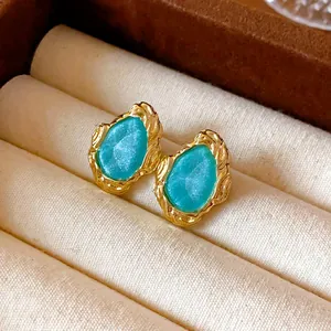 Nahaufnahme von Vintage-Ohrringen mit blauem Stein und goldener Textur.