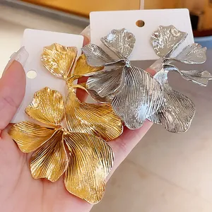 Detail shot of large gold and silver petal metal earrings with realistic textures