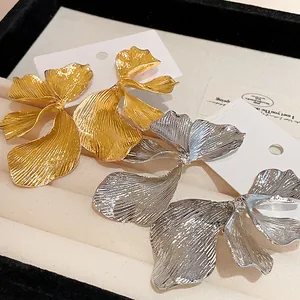 Detailed macro shot of textured gold and silver flower metal stud earrings on cards