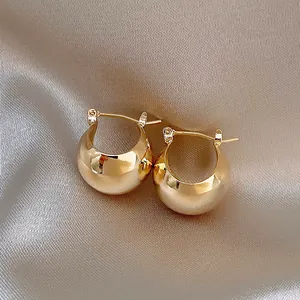 Eleganti orecchini a cerchio bombati placcati in oro 18 carati su sfondo di raso seta.