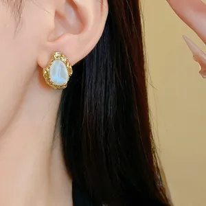 Detailaufnahme eines goldenen geometrischen Vintage-Ohrsteckers mit weißem Inlay