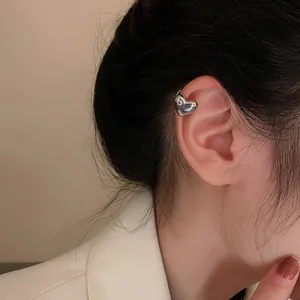 Primo piano di un ear cuff a cuore in argento con pietra luccicante sull'orecchio