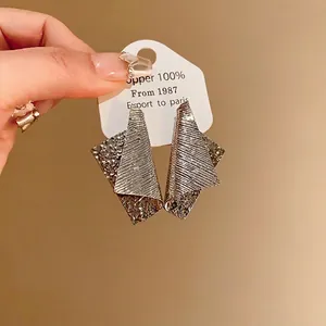 Unique irregular metallic earrings with ribbed and hammered texture in silver finish