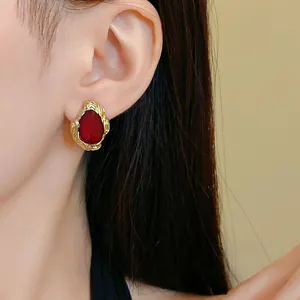 Nahaufnahme eleganter gold-roter Tropfenohrringe im Vintage-Palaststil am Modell