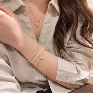 Elegant model wearing a layered 18K gold-plated zircon necklace and pearl bracelet set