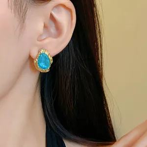 Nahaufnahme von Vintage-Ohrsteckern mit blauer Sternensand-Träne und Goldrand am Modell
