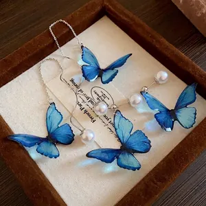 Elegant blue butterfly drop earrings with lustrous white pearls and silver needles.