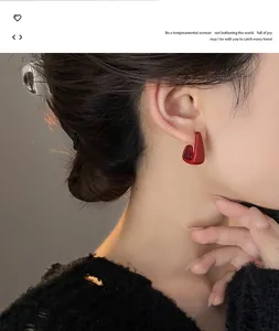 Close-up view of a minimalist red geometric drip oil earring worn by a model