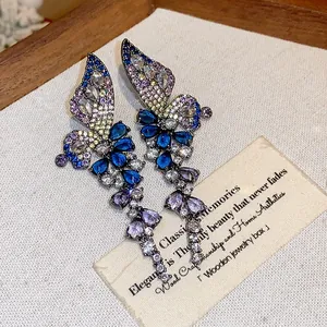 Macro view of colorful zircon butterfly wing earrings on a vintage wooden tray display