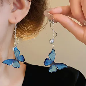Detailed view of elegant blue butterfly earrings featuring pearls and silver chain