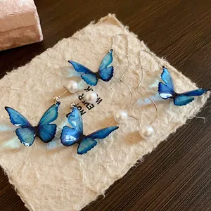 Detailed view of artistic blue butterfly earrings with elegant pearls on textured paper