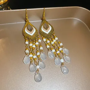 Detailansicht der ethnischen Quastenohrringe im Boho-Stil mit Goldperlen und Anhängern.