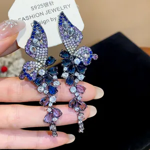 Macro detail of butterfly wing earrings with vibrant blue and purple zircon crystals