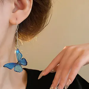 Detailed view of elegant blue butterfly pearl drop earrings worn by a model in soft light
