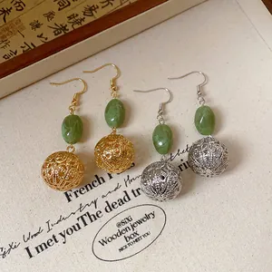 Close-up of retro New Chinese style earrings with green resin beads and hollow metal spheres