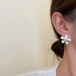 Close-up detail of a minimalist silver flower stud earring worn on the ear