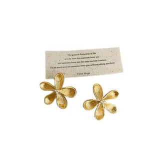 Elegant gold flower stud earrings with textured petals and silver needle backs