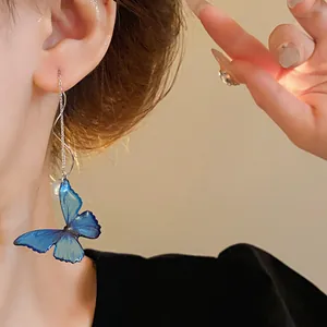 Detail shot of elegant blue butterfly earring with pearl and long chain on model