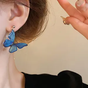 Detailed view of elegant blue resin butterfly drop earring worn by a female model