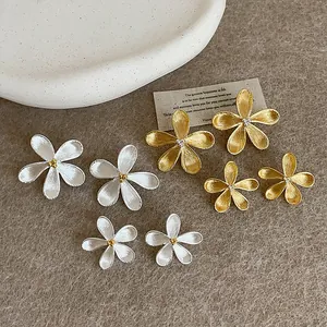 Macro view of minimalist flower stud earrings in silver and gold finishes and various sizes