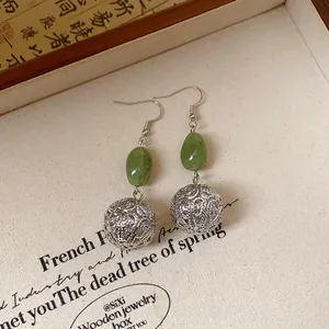 Macro view of vintage Chinese style earrings with green resin and silver filigree balls.