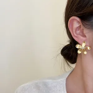 Close-up detail of elegant gold flower stud earrings worn on a model's ear lobe