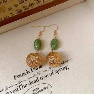 Detailed view of vintage New Chinese style gold hollow ball earrings with resin.